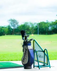 Golf bag with clubs on a driving range, showcasing a calm and inviting golf setting.