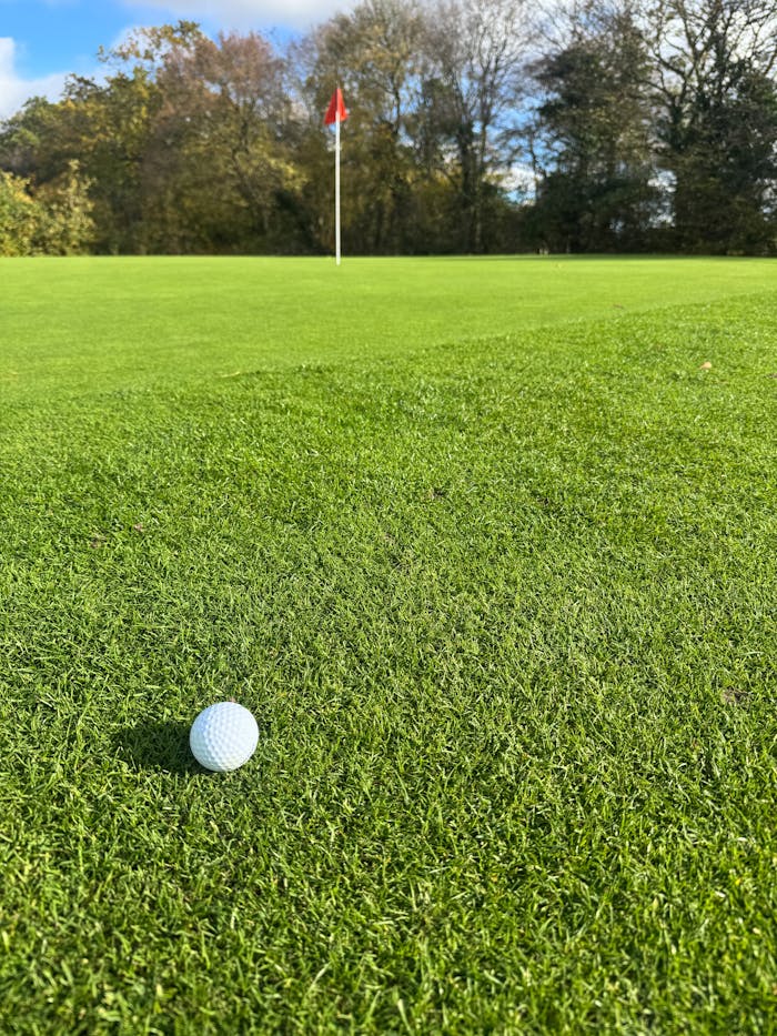 Close-up of a golf ball near the hole on a vibrant green golf course in England.