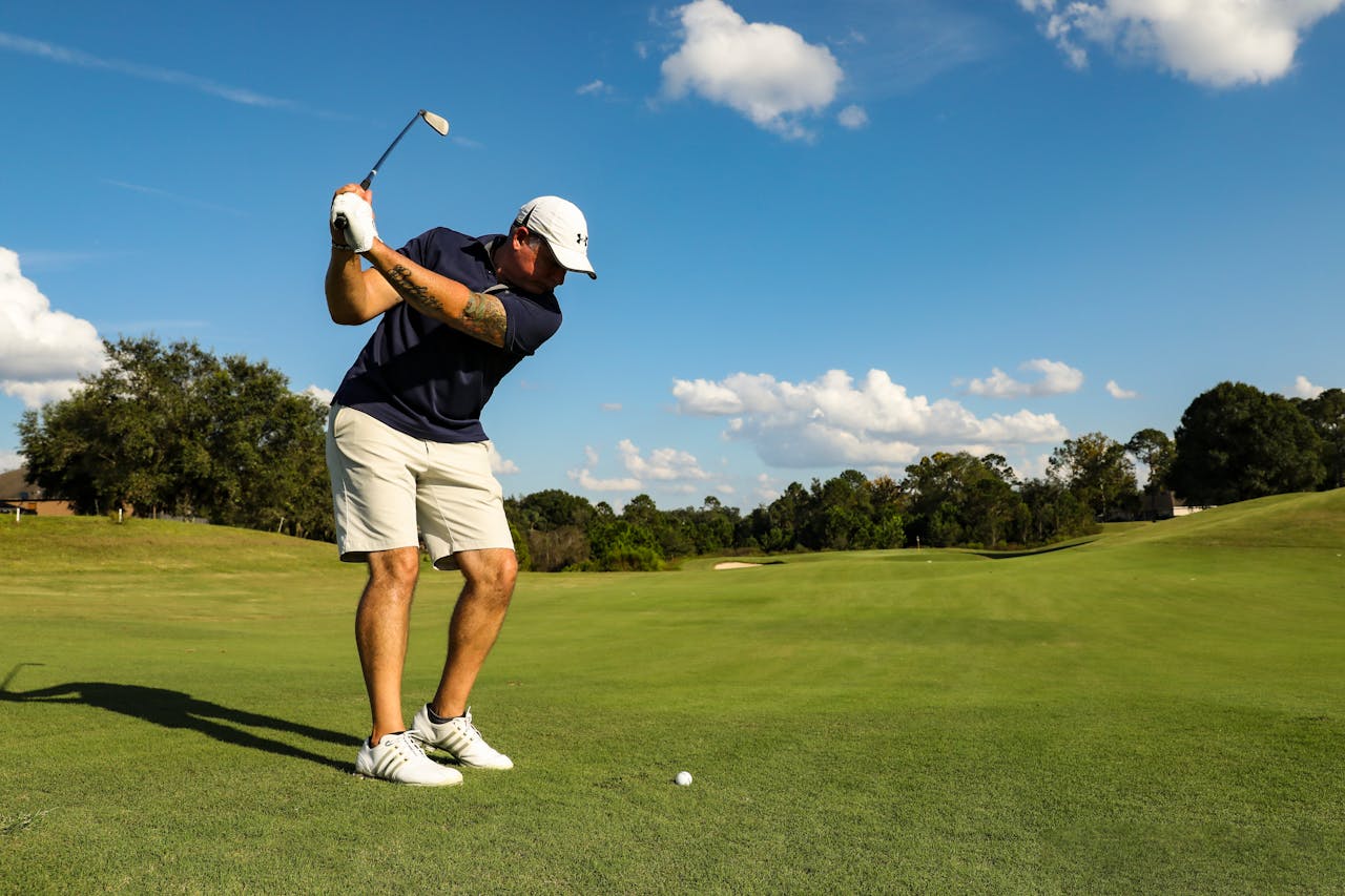 Man playing golf on a lush green course in Eustis, FL under a bright blue sky.